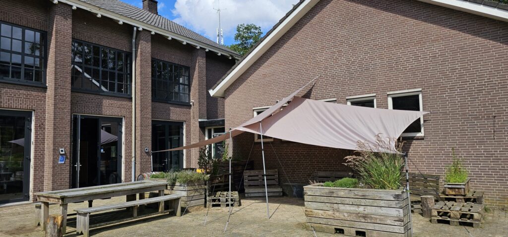 De ingang en het terras van de oude militaire sporthal bij Zaal huren Ede